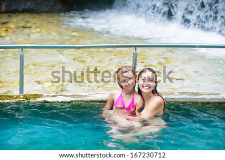 Mother and daughter at swimming pool smiling