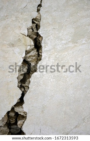 Big crack on the gray wall, abstract image of the vertical cleft. Close up. Selective focus. Copy space. Royalty-Free Stock Photo #1672313593