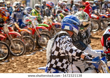 Image of two motorcycle riders ready to race with other riders in the background