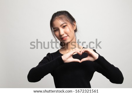Young Asian woman show heart hand sign on white background
