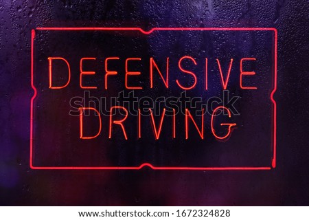 Neon Defensive Driving Sign in Wet Window