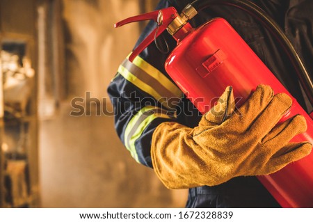 Close up hand Fireman,Firefighter holding the fire extinguisher. Royalty-Free Stock Photo #1672328839