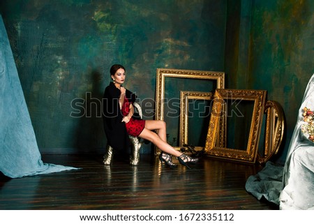 beauty rich brunette woman in luxury interior near empty golden frames, lifestyle people concept