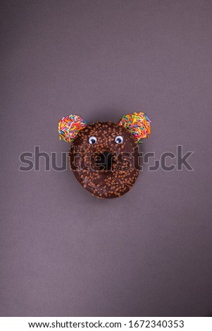 Chocolate donut with eyes on a dark background. Abstraction and minimalism.