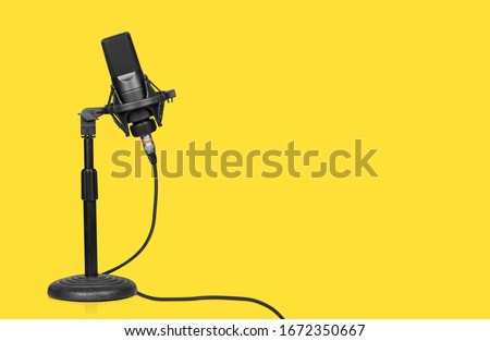professional microphone on a table stand over yellow background