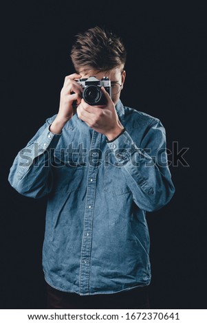 A man taking picture by old vintage camera. Man on dark background with camera.