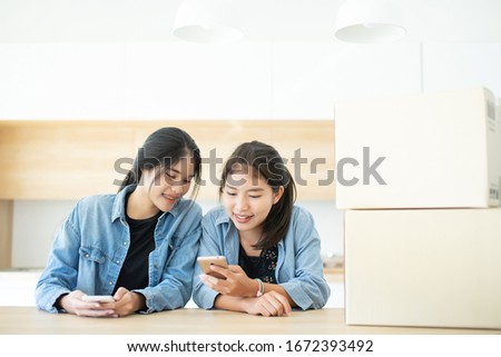 Two people friend Asian teenage ware jeans jacket or shirt using mobile phone and sharing data in social network, happy teamwork small business at home concept.