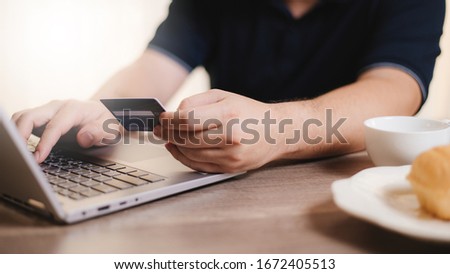 Online shopping on laptop, making payment by credit card, shopping in morning at home with coffee and bakery