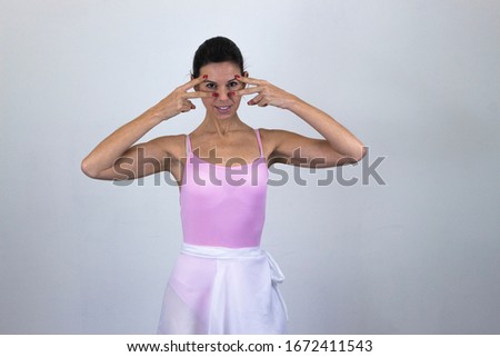 Portrait of ballet dancer, middle age woman model making victory or peace sign and covering her eye with it, isolated on gray background studio shot, ballet jersey, dark air. Place for your text in co