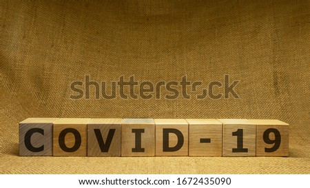 Wooden cubes with word COVID-19 on sackloth background. Pandemia and Covid-19 concept.