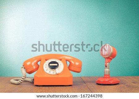 Retro red microphone and telephone on table front mint green background