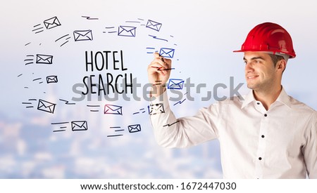 Handsome businessman with helmet drawing HOTEL SEARCH inscription, contruction sale concept