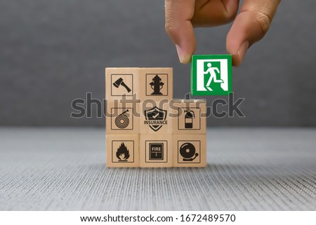 Close-up hand choose a wooden toy blocks with fire exit icon for fire safety protection concepts. Royalty-Free Stock Photo #1672489570
