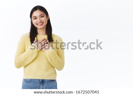 Cute humble and grateful asian girl thanking for congratulations, press hands to heart and smiling blushing from happiness and joy receiving gifts, looking touched, standing against white background Royalty-Free Stock Photo #1672507045
