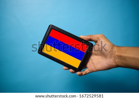 Man holding Smartphone with Flag of Armenia. Armenia Flag on Mobile Screen isolated On Blue Background