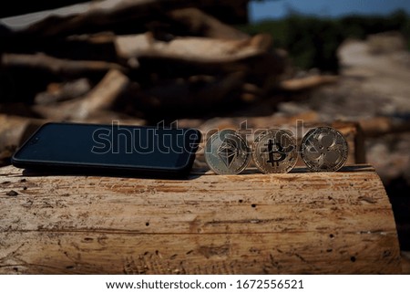 Cryptocurrency coins of ripple, bitcoin and Ethereum with a mobile phone/smartphone on a piece of wood