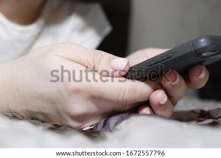 A hand holding a phone. Indoors