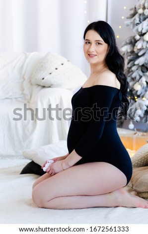 beautiful restrained exquisite pregnant brunette woman in black bodysuit on New Year holidays