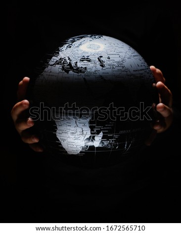 Hands of little child hold globe sphere map isolated on black background.  COVID-19 pandemic infection disease. Environmental pollution, ecological disaster our kids and future planet concept