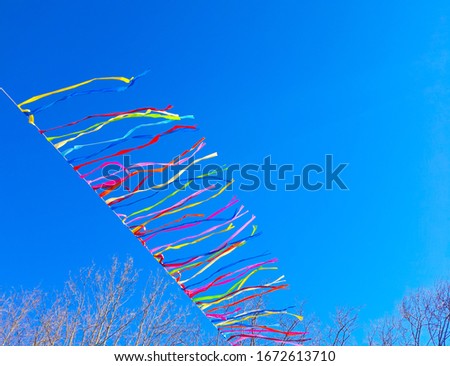 View of colorful ribbons in the wind against clear blue sky