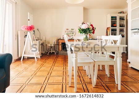 Beautiful bouquet of fresh flowers in a bright white living room with dining table