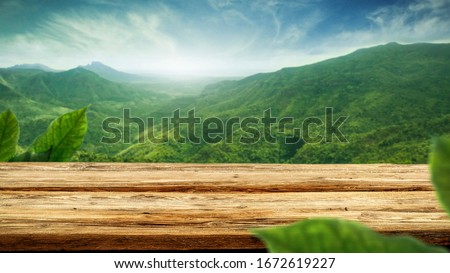 table background of free space for your decoration and blurred landscape of mountains.Blue sky with sun light and green small leaves.  Royalty-Free Stock Photo #1672619227