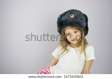 little girl in a winter military hat poses