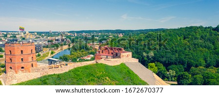 Beautiful panoramic aerial view photo from flying on Gediminas castle in capital Vilnius of Lithuania with Lithuanian flag on the tower and skyline of city center in the background. (series)