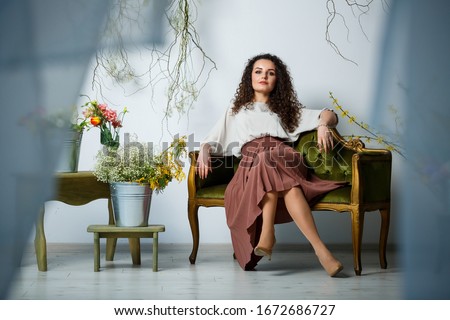 beautiful girl model with curls in a dress posing in beautiful arrangements. The beginning of spring with flowers