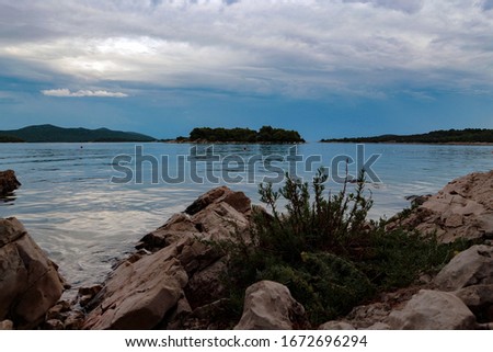                         Beautiful and colorful evening sunset at Croatian Murter island  rock stone beach just before the rainy storm       