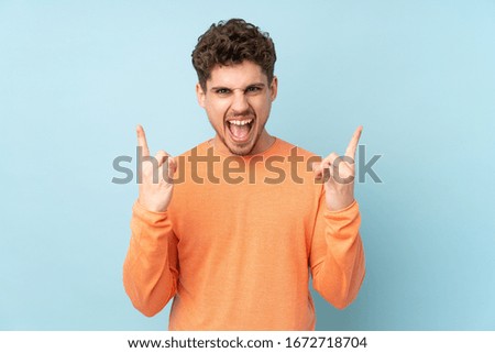 Caucasian man isolated on blue background making rock gesture