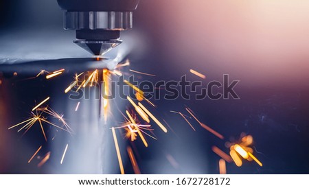 CNC gas cutting metal sheet, sparks fly. Blue steel color, modern industrial technology.