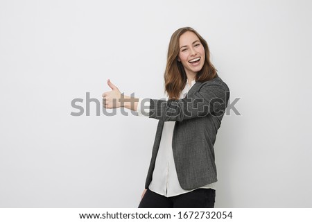 Businesswoman is pointing the thumb up while looking happy