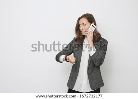 Young businesswoman talking on the phone while looking at the clock feeling stressed