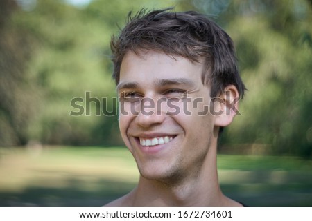Young attractive guy grining happily to the left with a sympathetic big smile