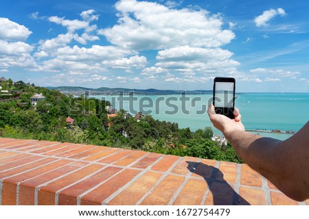 Tourist taking picture with his phone from Tihany abbey about one of the most beautiful view of the Lake Balaton