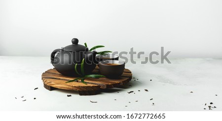 Asian food background with a tea set, cups, and teapot with free space for text on white stone background. Royalty-Free Stock Photo #1672772665