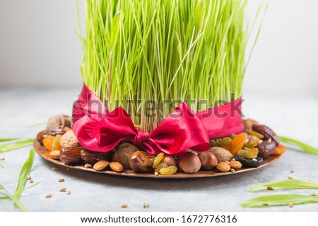 Happy Nowruz holiday background. Celebrating  various dried fruits, nuts, seeds, light background with green grass wheat, copy space top view