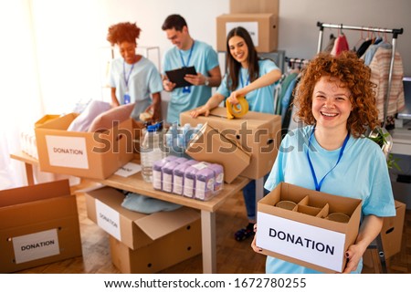 Woman and her colleague working in homeless shelter. Cheerful food drive manager. Happy diverse group of volunteers at food bank. Happy woman volunteers at a food bank  Royalty-Free Stock Photo #1672780255