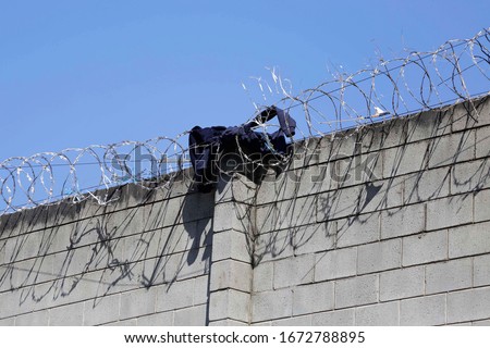 A sweatshirt is seen on a barbed razor wire fence installed on top of a concrete wall in Sao Paulo, Brazil.