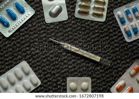 Thermometer on a dark structural background among various medicines