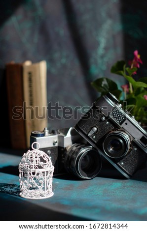 two old vintage cameras with books on the table