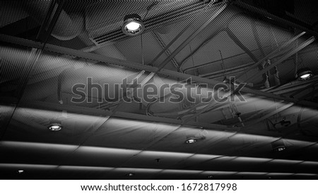
Black and white photo of a metal mesh ceiling with lamps