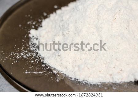 Coconut flour on grey background. Cream powder in a glass bowl. Isolated. Alternative gluten-free flour for baking and cooking. Ketogenic diet.