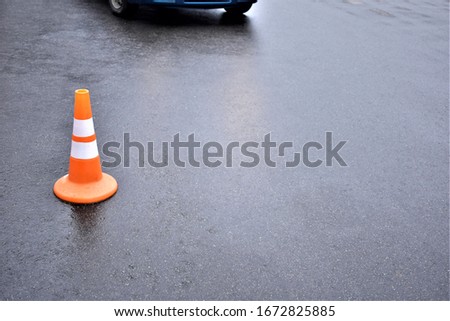 plastic cone for fencing on the road and an approaching car