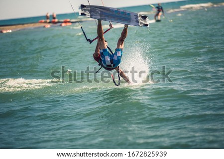 Professional kiter makes the difficult trick on a river. Kitesurfing Kiteboarding action photos man among waves quickly goes