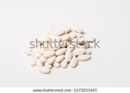 A pile of white oval-shaped tablets on a white background. View from the side. Isolated