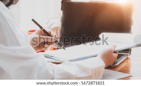 Hand of businesswoman writing on paper in office