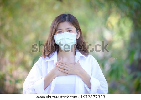 Corona virus, or Covid-19, is spreading all over the world. Business women Sit in the park wear masks Because he was infected with a viruses and showing trumb up sign.on the park background