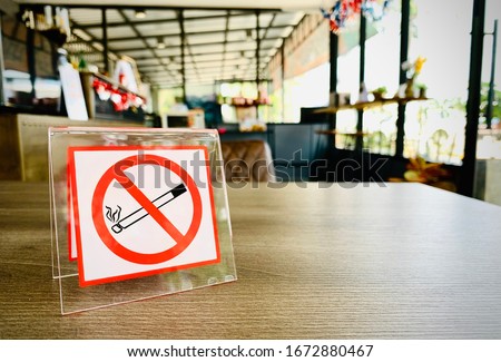 No smoking sign on a wooden table of coffee shop in hotel room. Concept photo of banning smoking in public area, medical, health, free smoking, hazard and addiction. Royalty-Free Stock Photo #1672880467